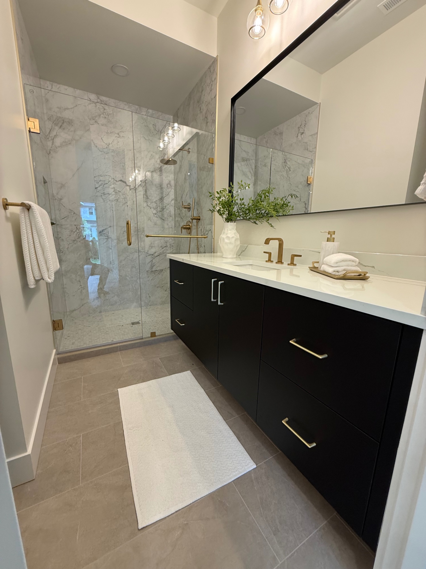 Modern bathroom with marble shower and dark vanity