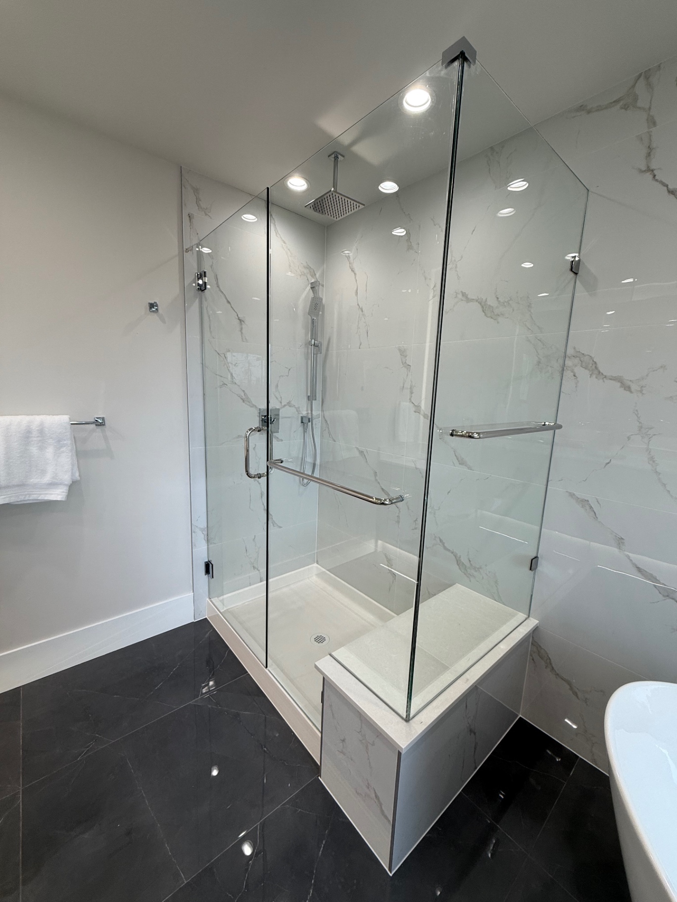 Marble tile shower with glass enclosure and bench